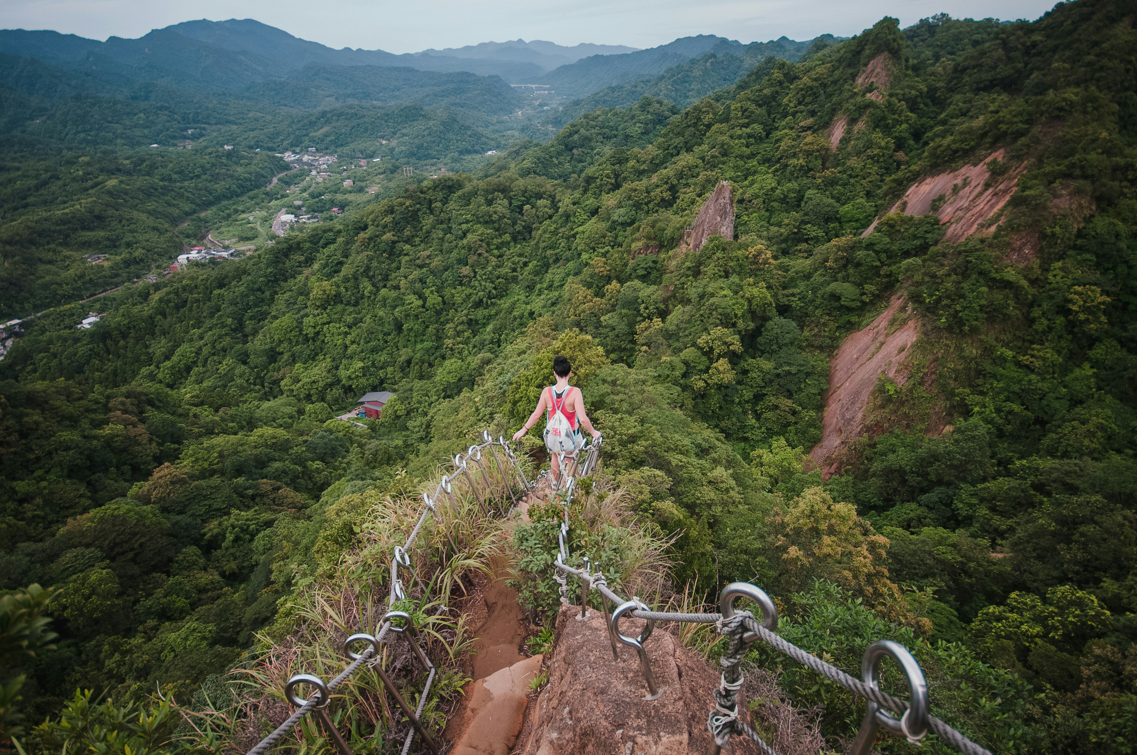 woman in white shirt and blue denim jeans standing on brown rocky mountain during daytime